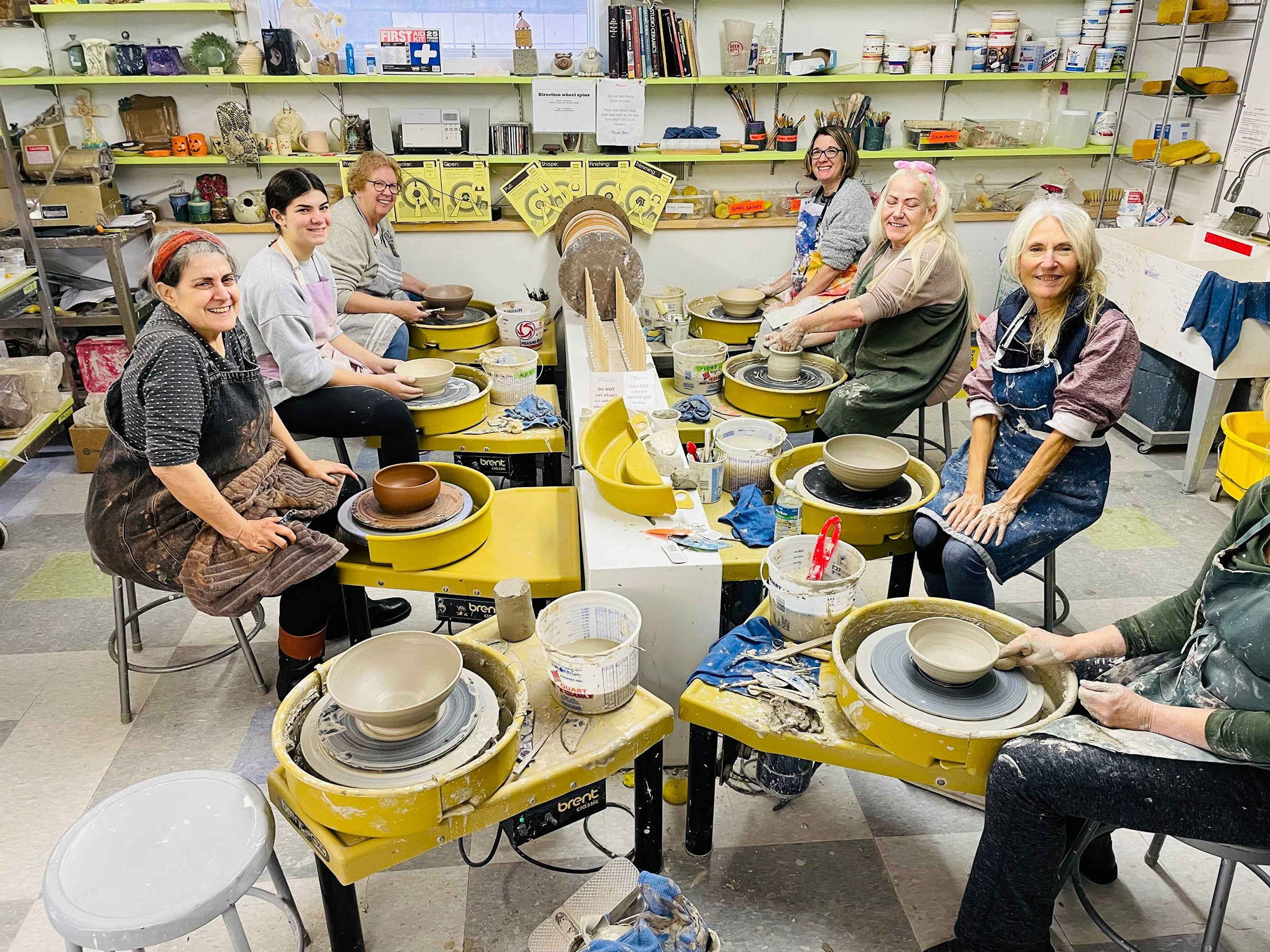 Our pottery open studio group smiling at the pottery wheels.